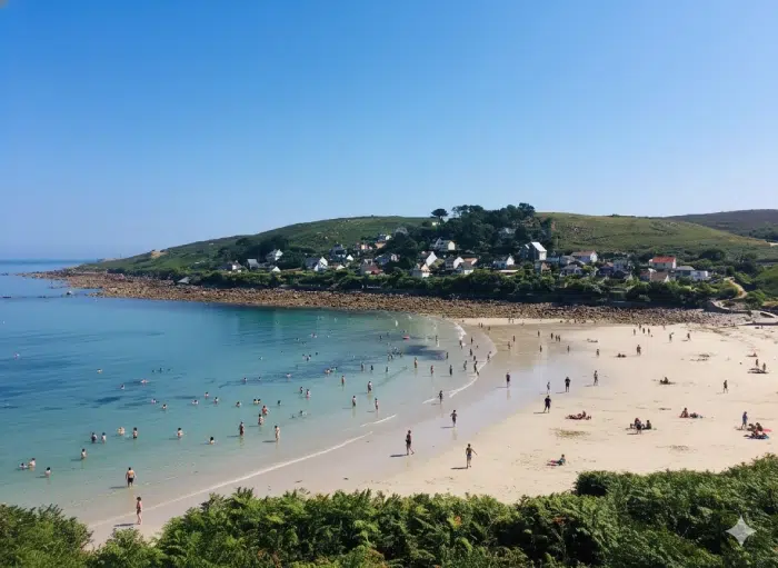 Camping Cherbourg, plage bordée par la mer avec maisons sur les hauteurs