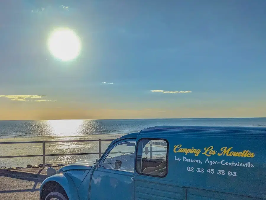 Voiture ancienne devant la mer au coucher de soleil près du camping Les Mouettes à Agon-Coutainville dans la Manche.