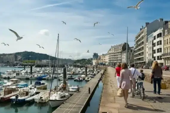 Camping Cherbourg, promenade en bord de port avec bateaux amarrés, passants et mouettes