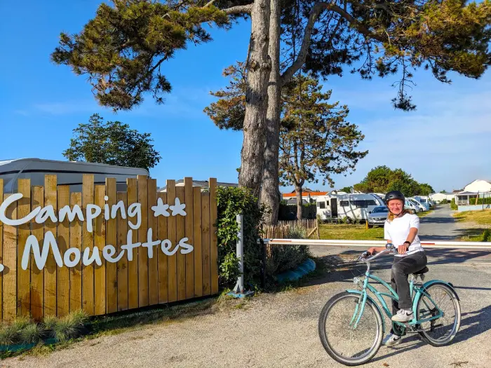 Jeune vacancière à vélo à l’entrée du camping Les Mouettes, près de Granville en bord de mer